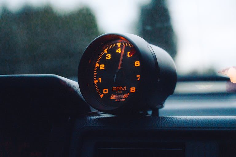 A glowing RPM gauge mounted on a car dashboard, emphasizing speed and automotive focus.