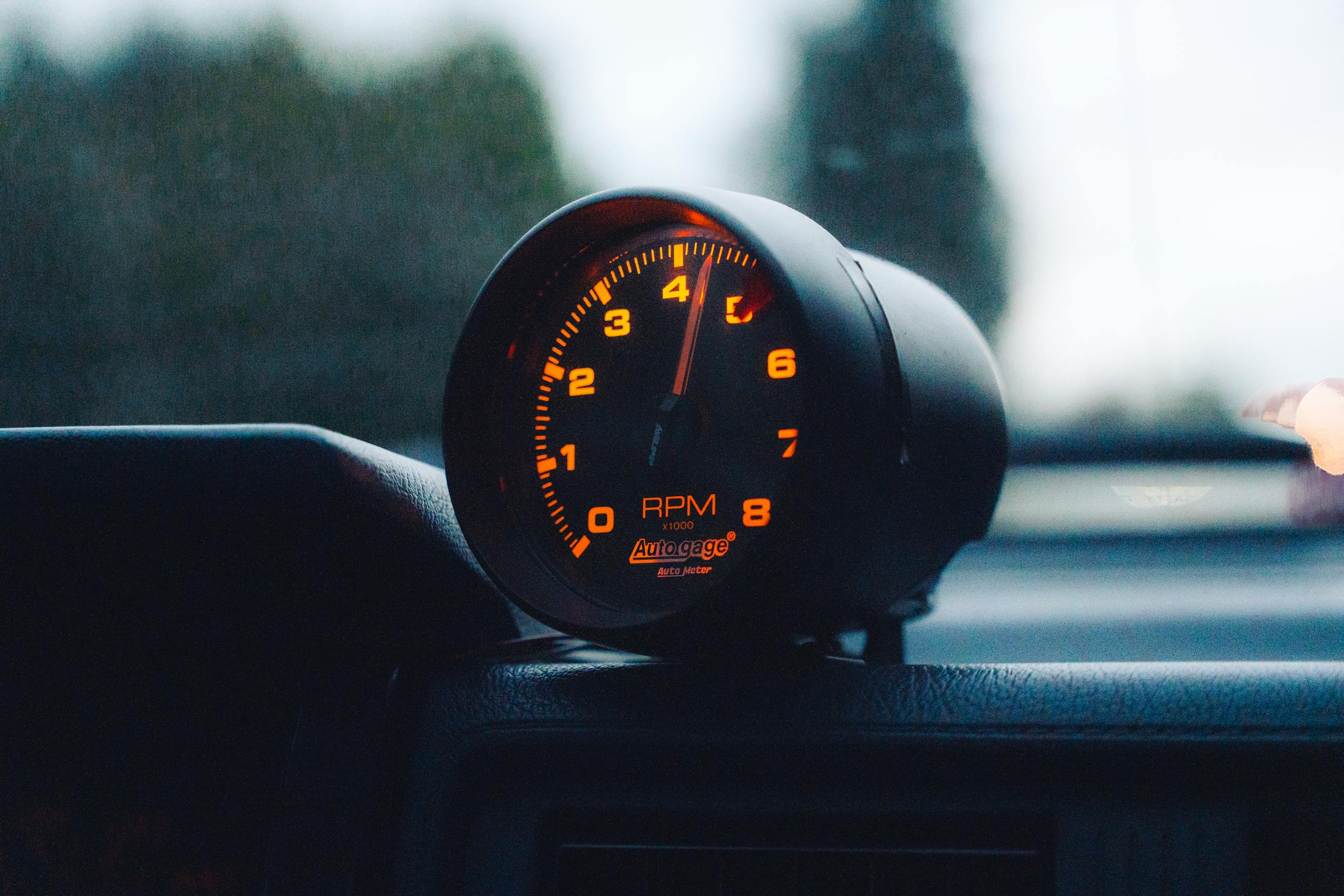 A glowing RPM gauge mounted on a car dashboard, emphasizing speed and automotive focus.